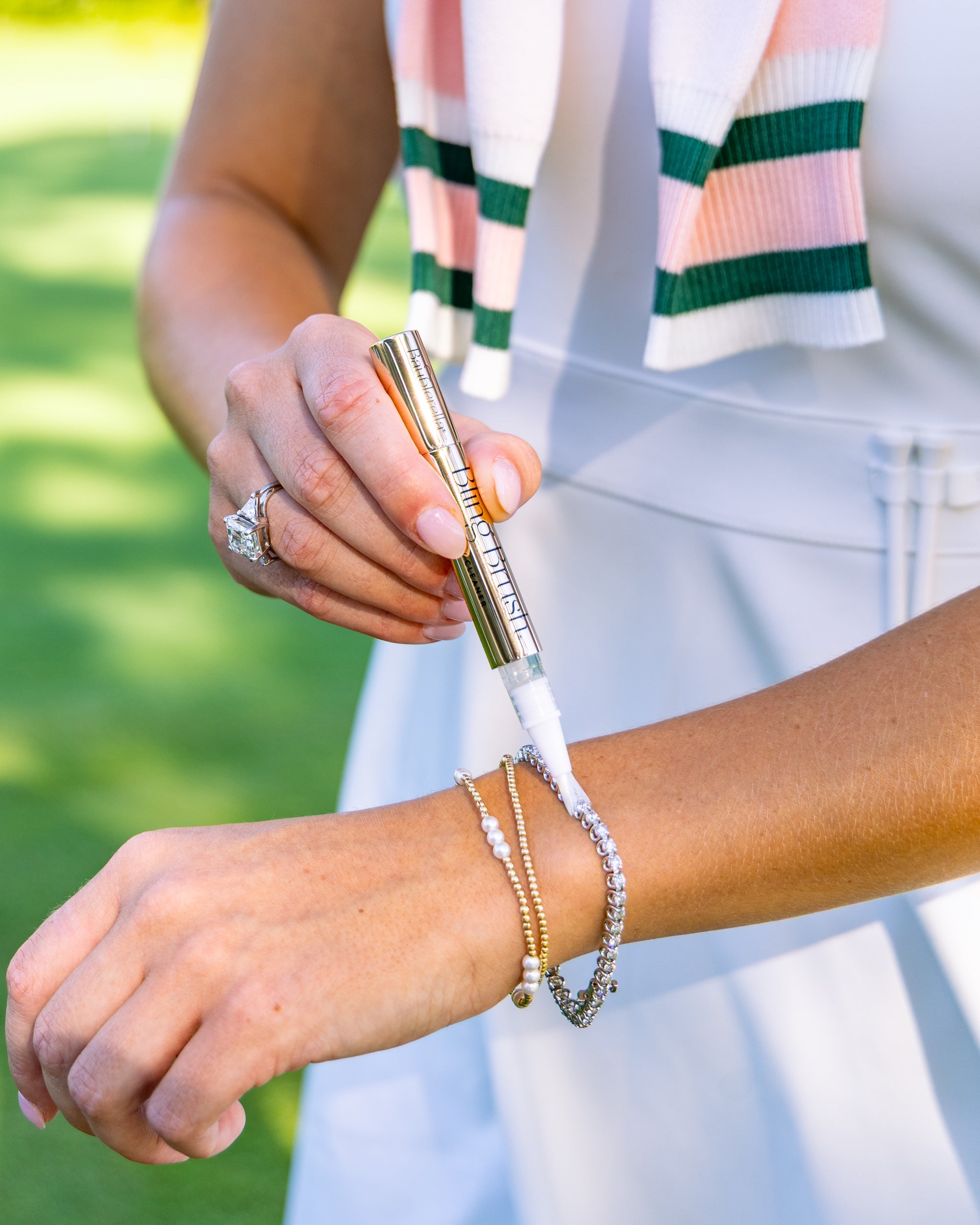 Person cleaning diamond tennis bracelet with the Bling Brush Jewelry Cleaning Pen