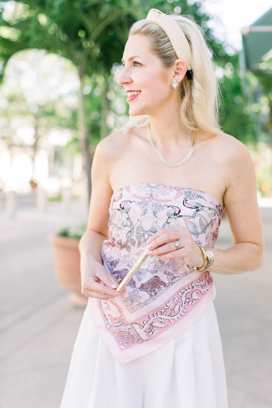 Woman wearing a floral strapless top holiday a Bling Brush Jewelry Cleaning Pen.