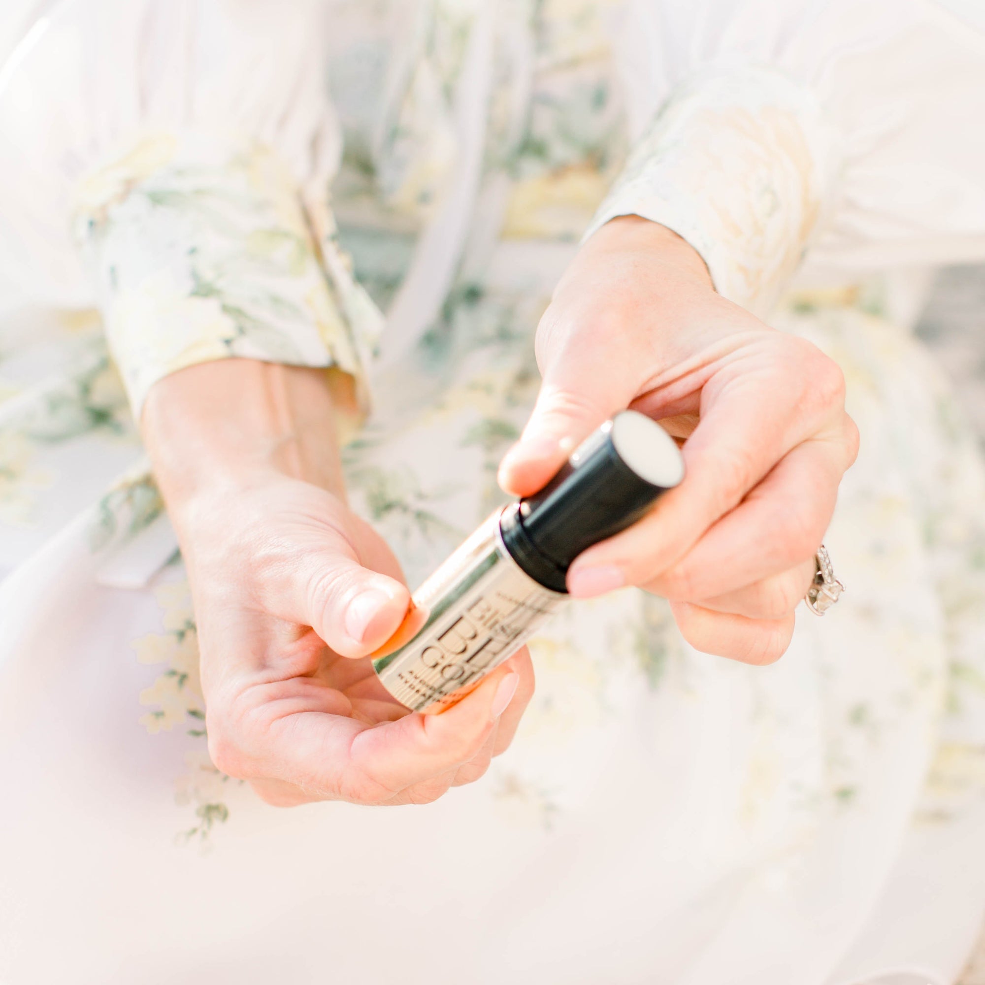 Woman in a floral dress holding a blister prevention balm