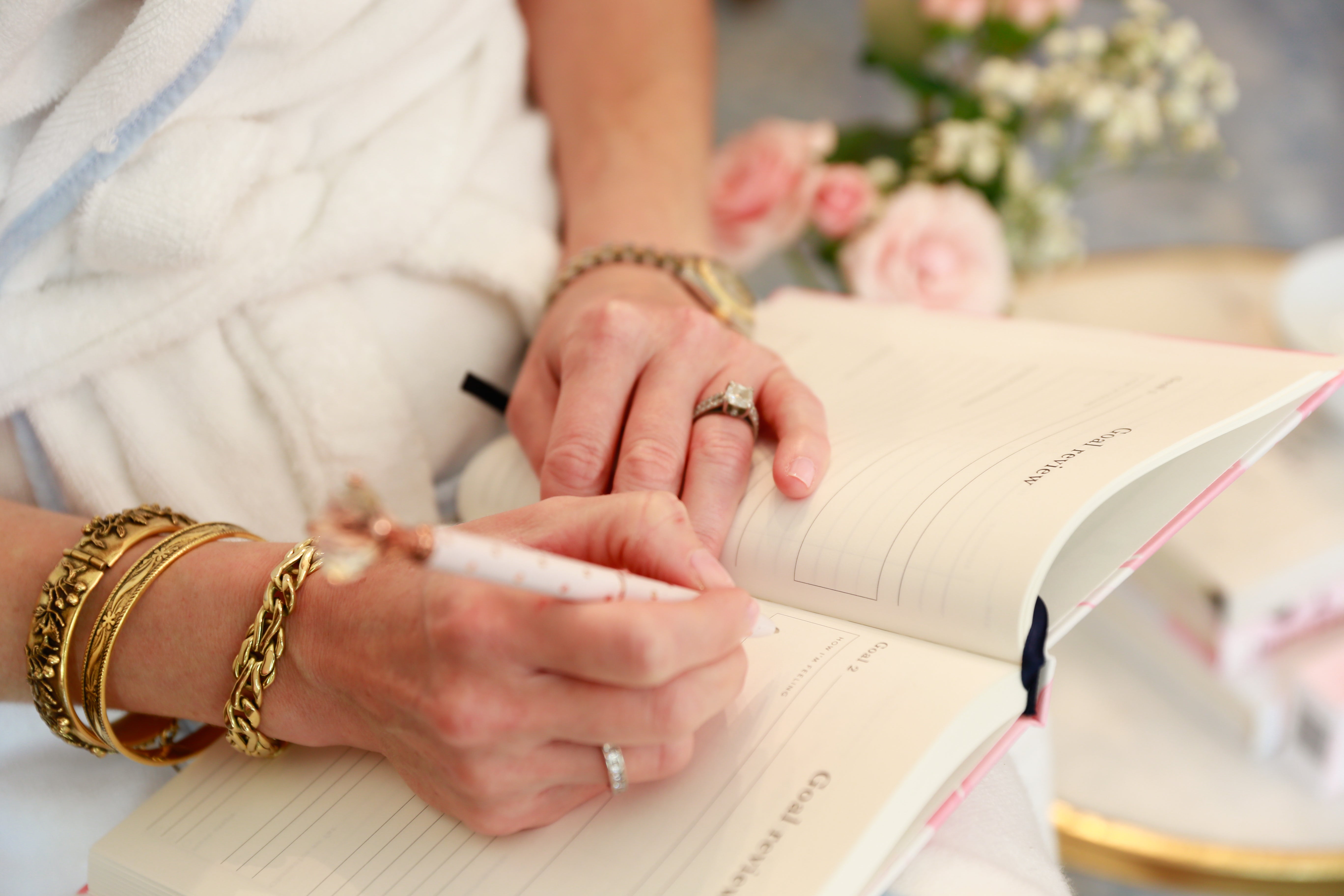 Girl wearing vintage gold bracelets and writing in a Papier journal with a diamond topped pen.